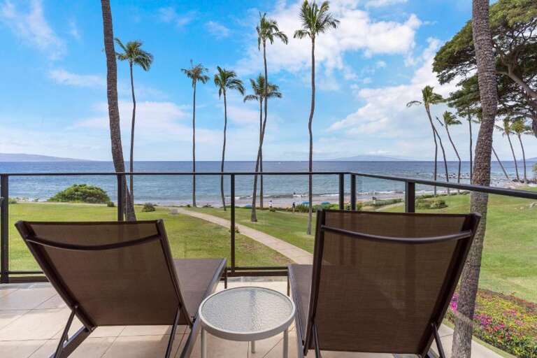 Balcony View Of A Serene Sea Setting With Slender Palms