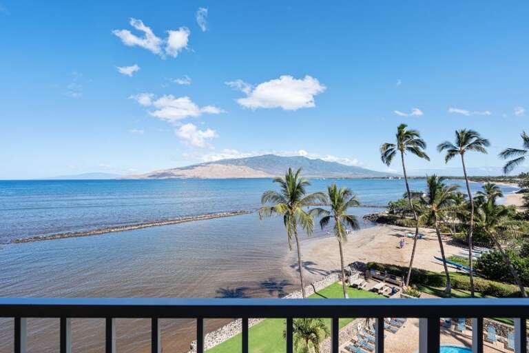 Breezy Balcony View Of Beach, Palm Trees, And Distant Mountain