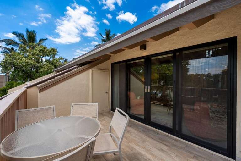 Beige Building, Black Glass Sliding Doors, Wooden Deck, Outdoor Seating Under Sunny Skies