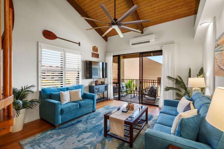 Bright Blue Sofas Balance Beneath Beamed Ceilings, Leading To A Breezy Balcony