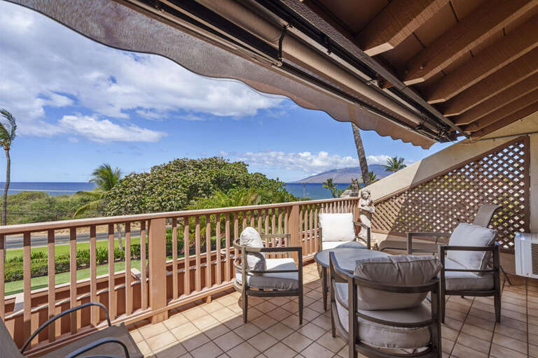 Balcony View Of Blue Sea, Bright Sky, Brown Railing, And Seating Area