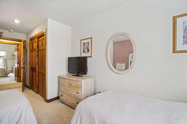 There is a tv and a closet in this bedroom. There is a tv and a closet in this bedroom.