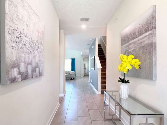 Hallway With Glossy Floor, Bright Paintings, Stairs, And Yellow Flowers