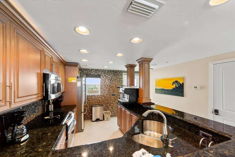 Vacation Rental Kitchen With Polished Stone Counters, Stainless Steel Appliances, And Vibrant Wall Art