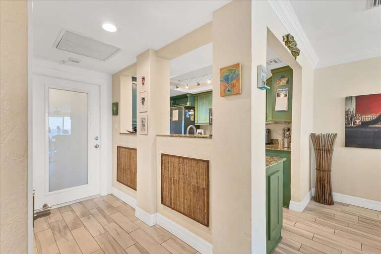 Bright, Breezy Interior With Beige Walls, Wooden Floors, And Green Kitchen Glimpse