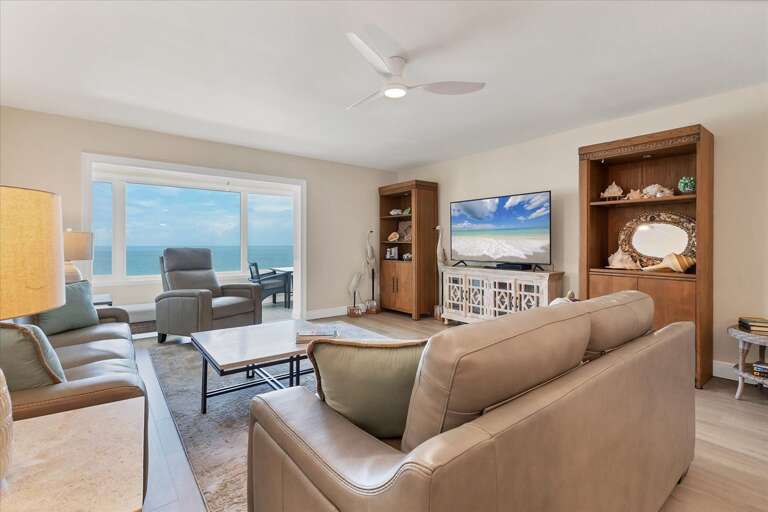 Serene Seaside Living Space With Sandy Shades And Sleek, Subtle Seating, Sprawling Sea Views Visible Through Large Balcony Doors