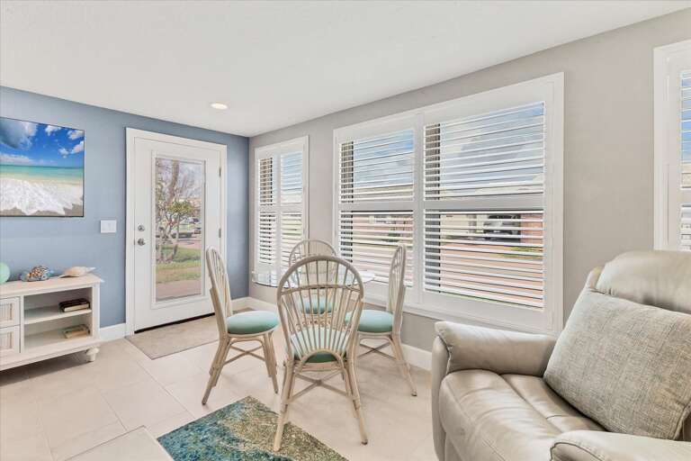 Bright, Breezy Room With Blinds, Beige Sofa, Blue Chair, And Beach View