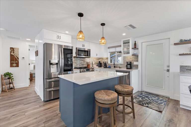 Bright Blue Kitchen Island, Stainless Steel Appliances, Pendant Lights