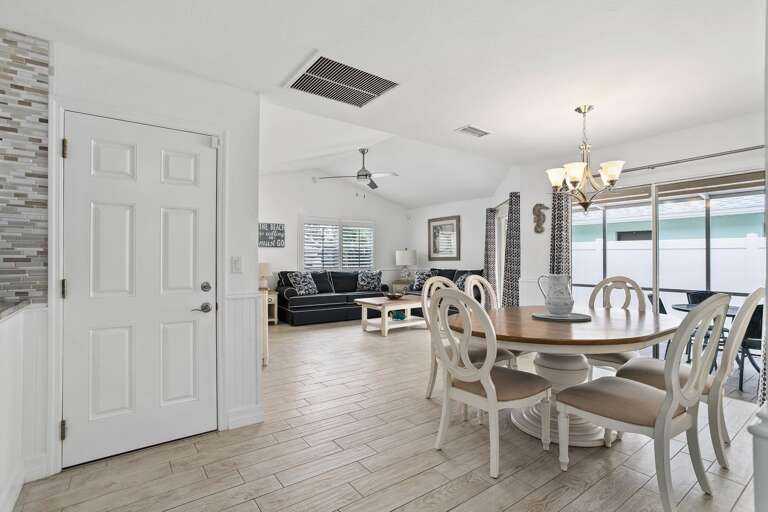 Spacious Space With Sleek Sofa, Light Dining Chairs, Chandelier Lighting Spacious Space With Sleek Sofa, Light Dining Chairs, Chandelier Lighting