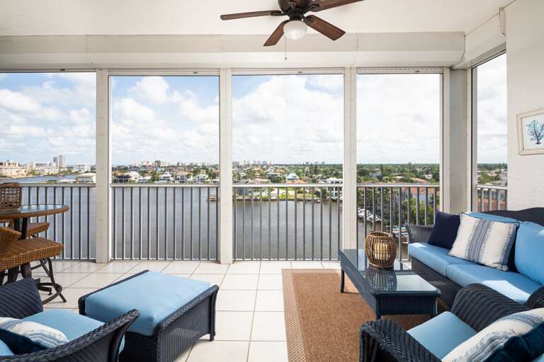 Balcony View With Blue Sofas, A Dining Set, And A Scenic Skyline