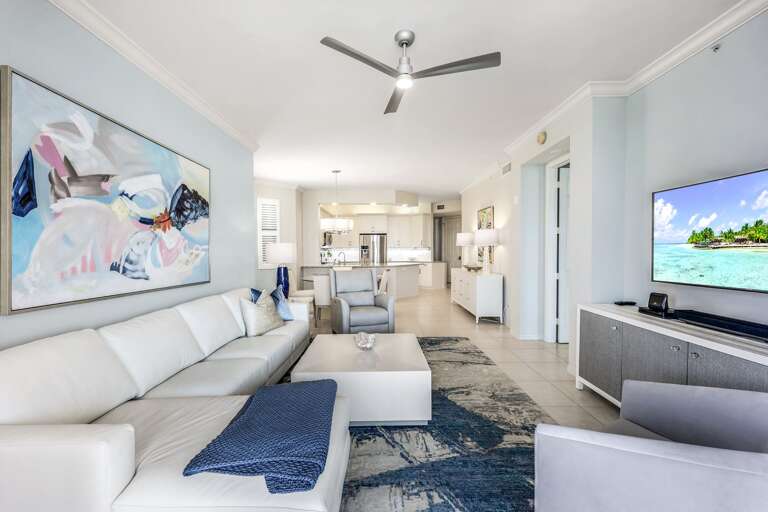 Bright Living Room Interior In Vacation Rental With White Sectional Sofa And Mounted TV