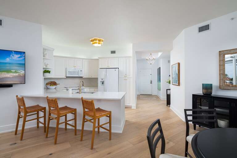 Spacious, Sleek White Kitchen, Wooden Bar Stools, Lighted Living Space