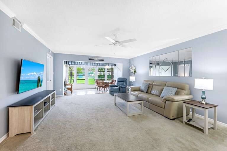Spacious Living Room Leading To Lush Lawn, Large TV, Light Sofa, Glass Doors Spacious Living Room Leading To Lush Lawn, Large TV, Light Sofa, Glass Doors