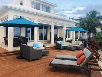 Oceanfront pool deck area furnished for lounging and dining.