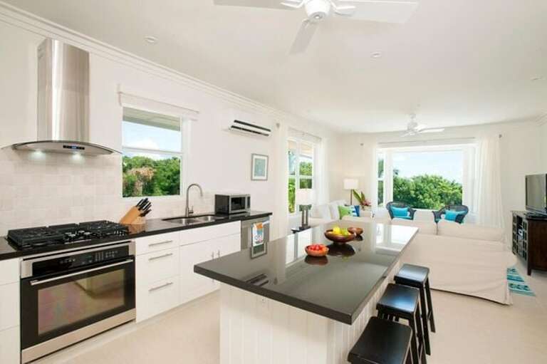 Modern island kitchen finished with black granite and stainless steel.