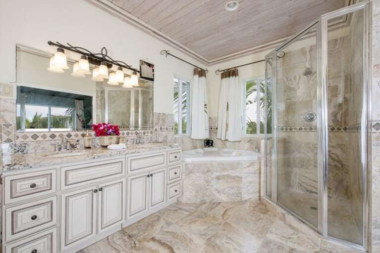 This classic bathroom includes a toilet, 2 sinks, a quality glass shower, and a large spa for guests to enjoy.