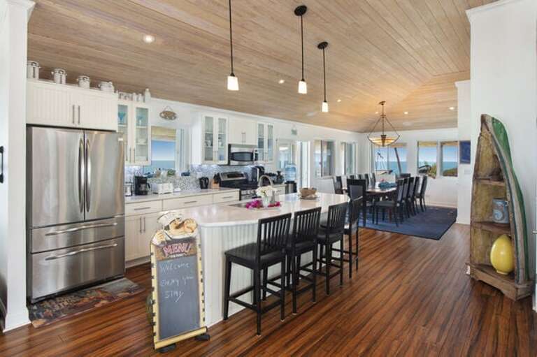 Full luxury kitchen with an oversized island with 4 bar stools, GE Profile appliances, and elegant quartz countertops.