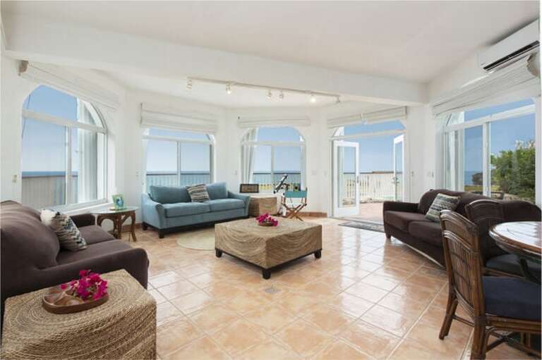 The Gazebo Suite living room with a wall of glass facing the sea.  This suite, which contains the fifth bedroom, can be added to the reservation for $100 per night.