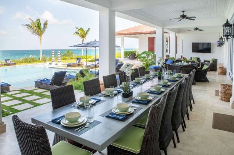 Outside covered veranda dining area with seating for 20 and a round pedestal breakfast table for 4.