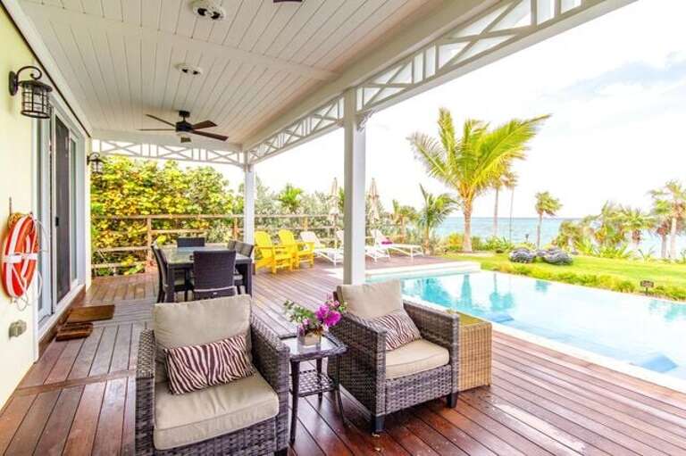 Pool deck with beach and ocean views, furnished for lounging and for dining.
