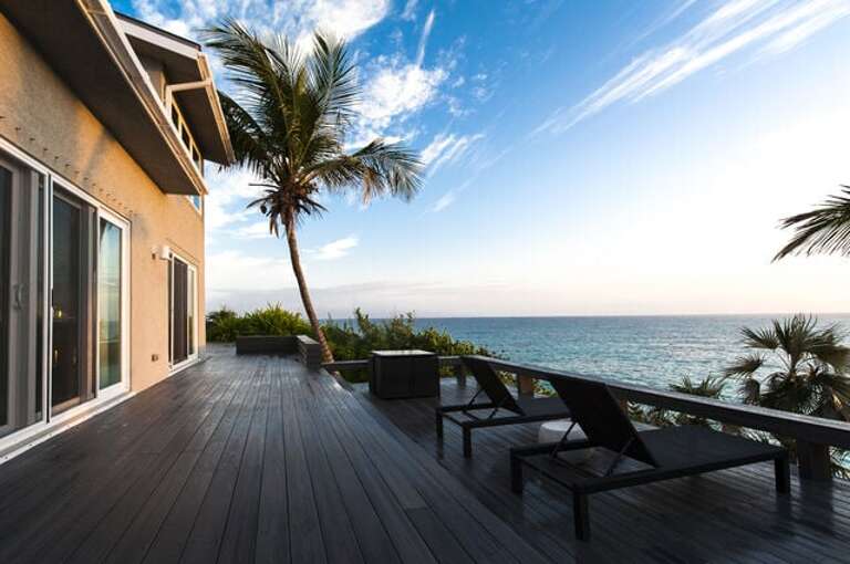Oceanside deck at Sunrise Villa with outdoor seating areas, waterside dining and stairs winding gently to the sea.