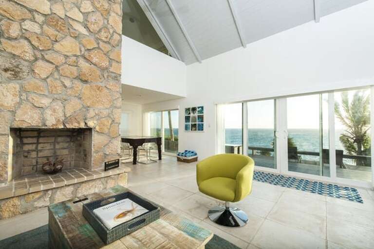 Sliding glass doors invite you to an oceanside deck with outdoor seating areas, waterside dining and stairs winding gently to the sea.