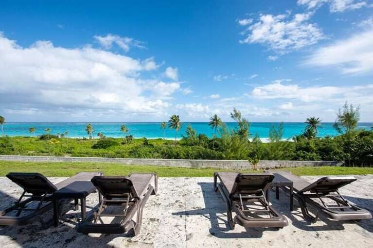 Patio with lounge chairs, steps from the ocean.