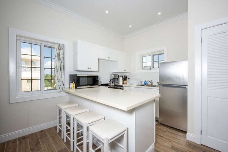 Luxurious kitchen finished in quartz and stainless steel next to washer and dryer closet.
