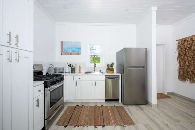 The kitchen, finished in quartz and stainless steel, is fully equipped with a gas range and oven, refrigerator, dishwasher, microwave, and all necessary cookware, dishes, and flatware.