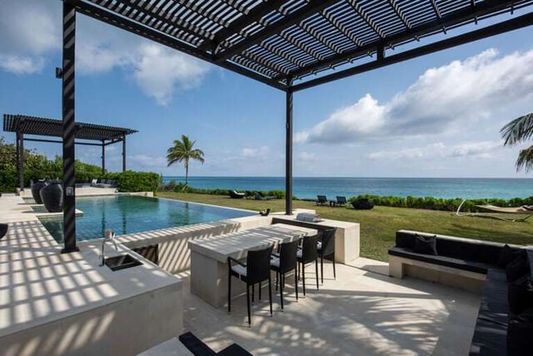 Outdoor kitchen equipped with a BBQ, sink and kitchen island with 4 bistro height chairs.