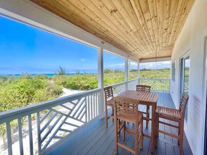 Upper deck with hammock chairs and 4-top teak table facing ocean.