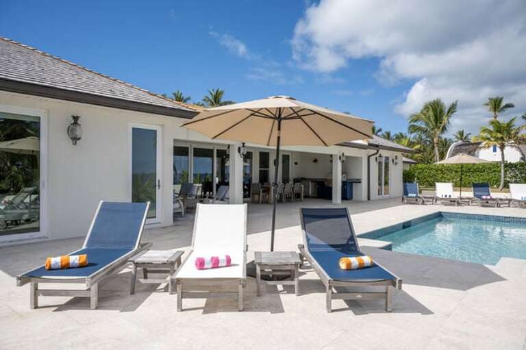 The patio is furnished for lounging and dining, features an outdoor kitchen with a gas grill.