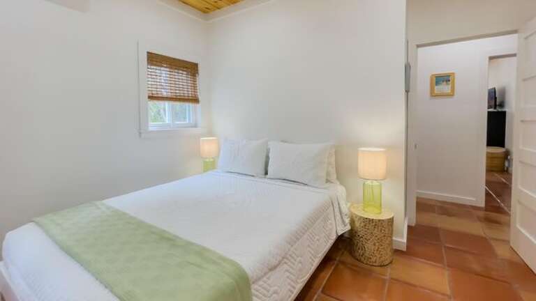The guest bedroom is furnished with a queen bed and access to a full bath with walk-in shower across the hall.