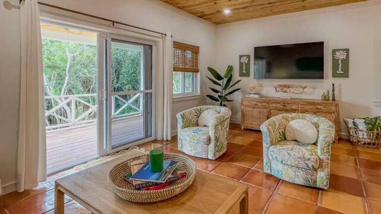 The living area is equipped with a sofa, chairs, and a 65-inch flat screen TV.