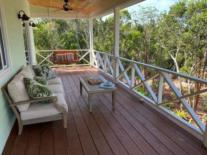 The shady Palmetto House deck overlooks a private garden with a fire pit and is furnished for lounging or swinging on the porch swing.