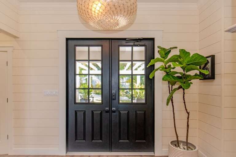 Grand covered porch with a stately set of double doors.