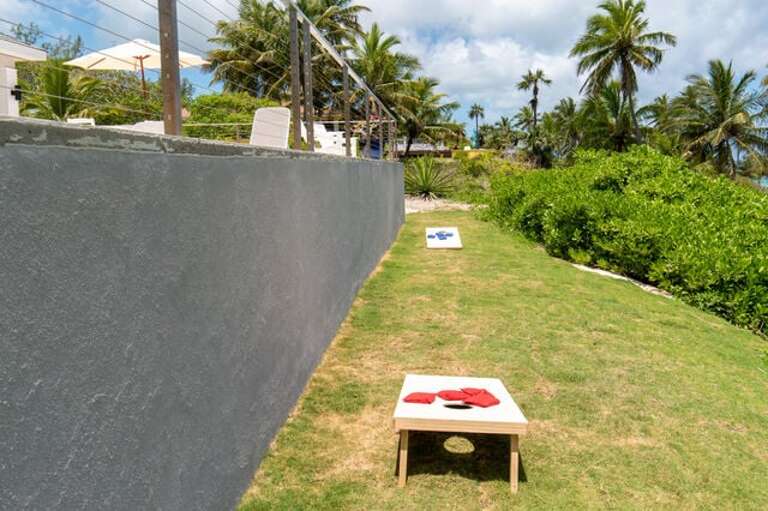Back yard beside pool deck, set up for cornhole.