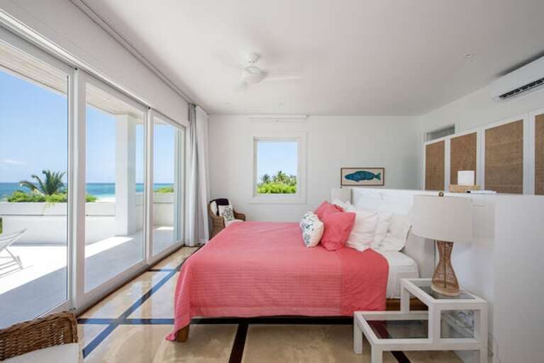 Master suite with king bed, en-suite full bath, and a wall of glass overlooking the beach and ocean.