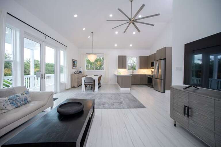 The living area is furnished with a leather sectional sofa and a 65-inch flat screen TV.