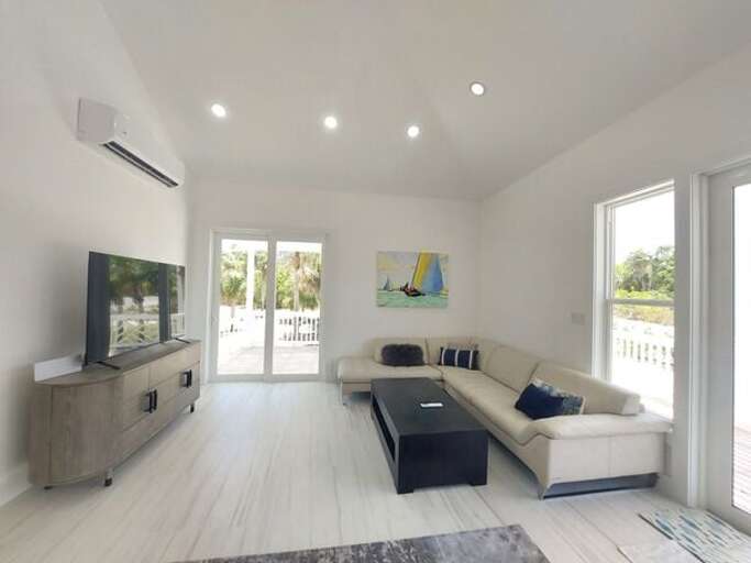 The living area is furnished with a leather sectional sofa and a 65-inch flat screen TV.