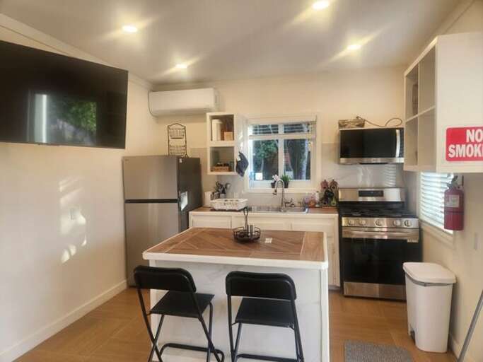 Modern island kitchen is equipped with a refrigerator, gas range and oven, and a microwave.