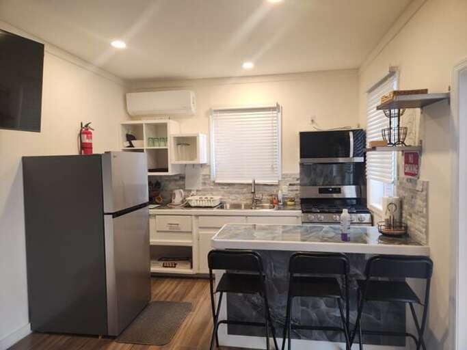 Modern island kitchen is equipped with a refrigerator, gas range and oven, and a microwave.