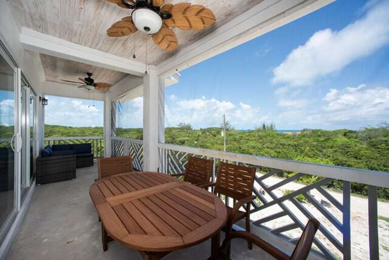 Screened balcony with six-seat teak dining table and chairs.