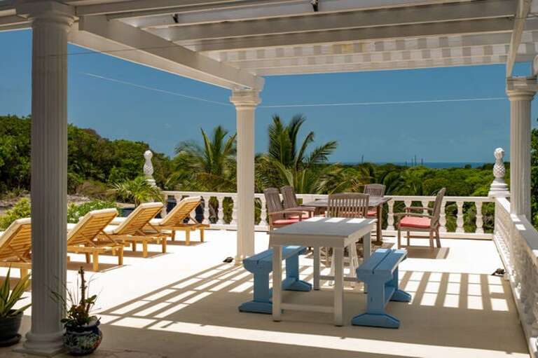 Outdoor living area with dining table and cushioned lounge seating.