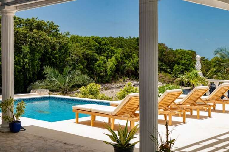 A sun deck with cushioned chaise lounges and tables and chairs.