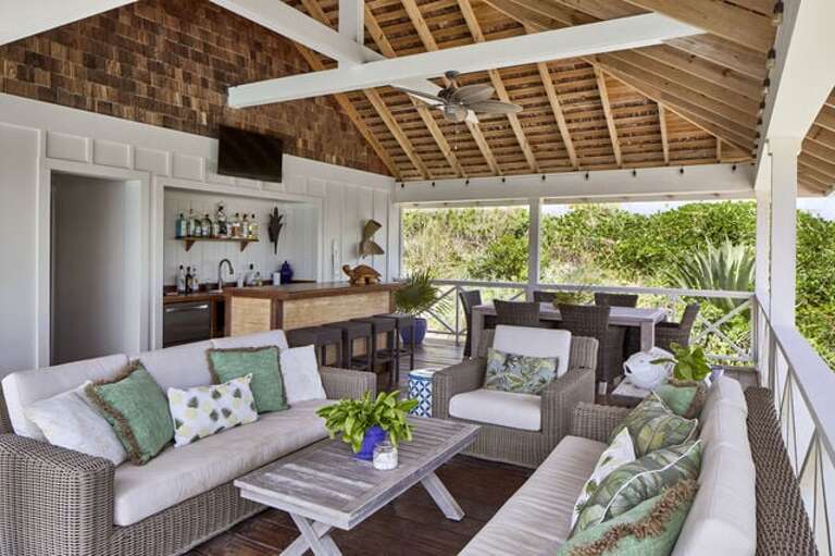 The pool house features a stocked bar, a lounging area with two sofas and an oversized chair, and a dining area equipped with a six-seat dining table.
