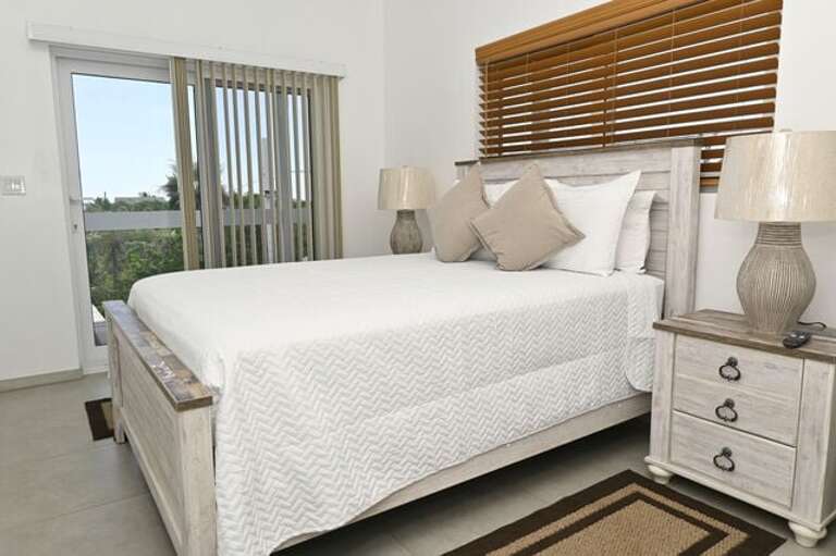 Sapphire Cottage second master bedroom with ocean views. Each bedroom has a queen bed, a 65-inch wall-mounted flat-screen TV.