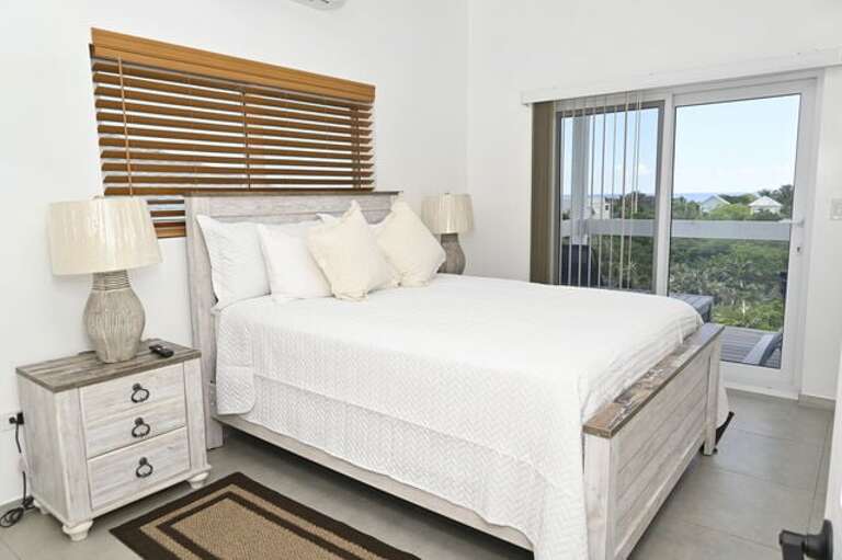 Sapphire Cottage master bedroom with ocean views. Each bedroom has a queen bed, a 65-inch wall-mounted flat-screen TV.