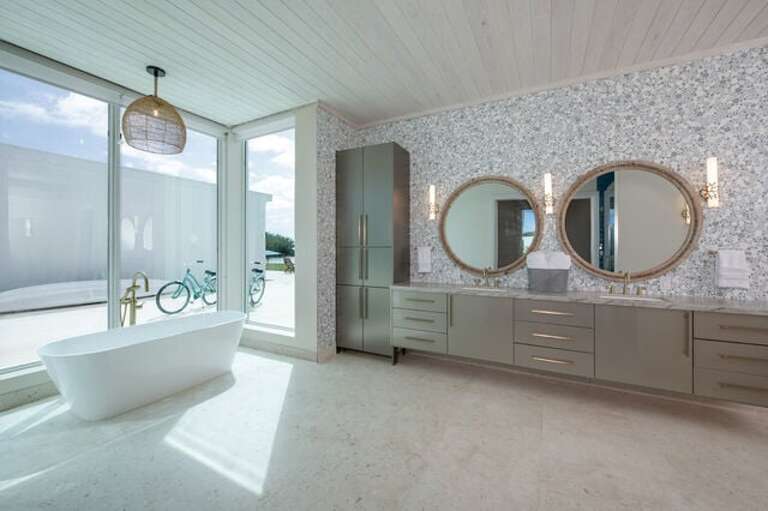Master bath with dual sinks, walk-in shower, and soaking tub with ocean view.