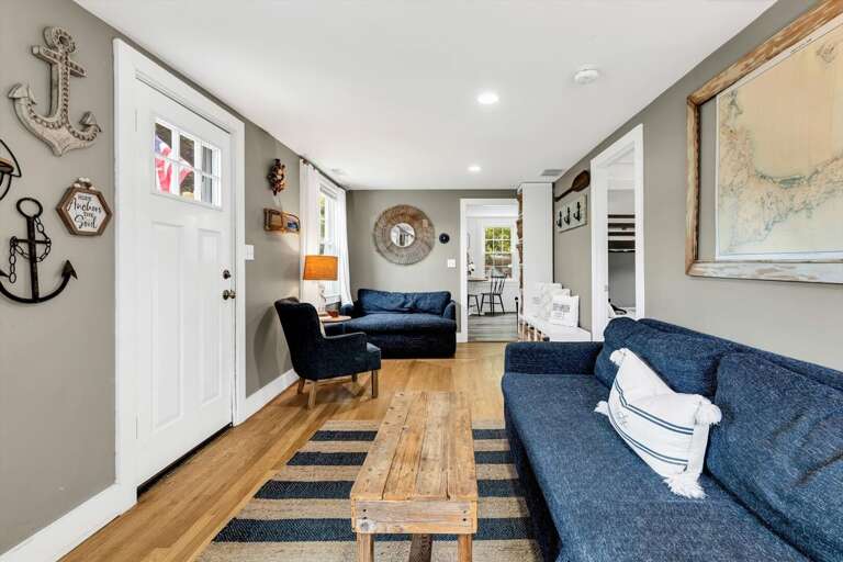 Nautical-themed Living Room With Blue Sofas, Wooden Table, And Wall Decor